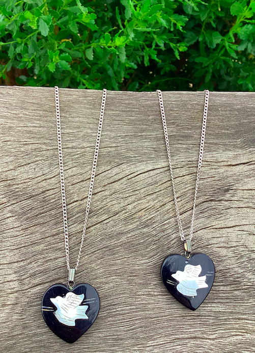 Two 1970's-90's vintage black heart with white bird pendants on silver chains