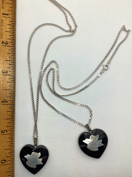 Two 1970's-90's vintage black heart with white bird pendants on silver chains